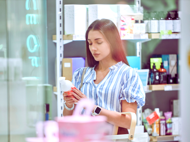 Customer in a skincare store carefully examining a product, symbolizing smart product choices for eco-conscious salons and businesses.