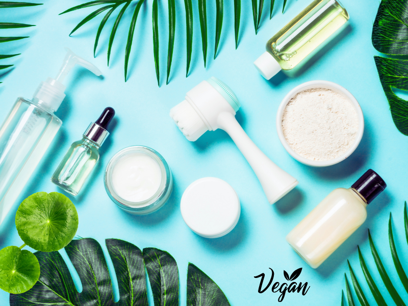 Flat lay of vegan skincare products with green leaves.