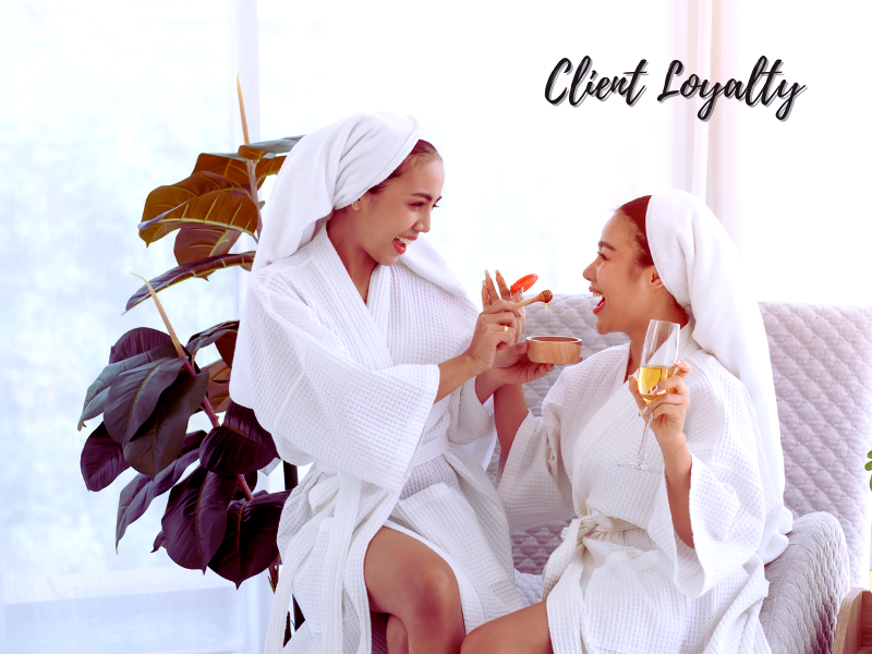 Two women in spa robes sharing a joyful moment, embodying client loyalty and the benefits of advanced skincare solutions. 