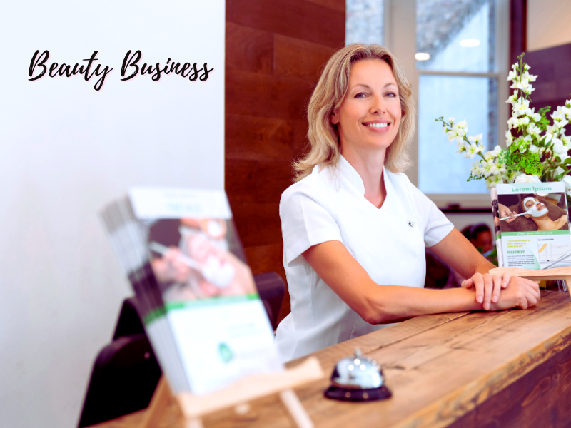 A smiling professional at a reception desk with "Beauty Business" text, surrounded by brochures and flowers.