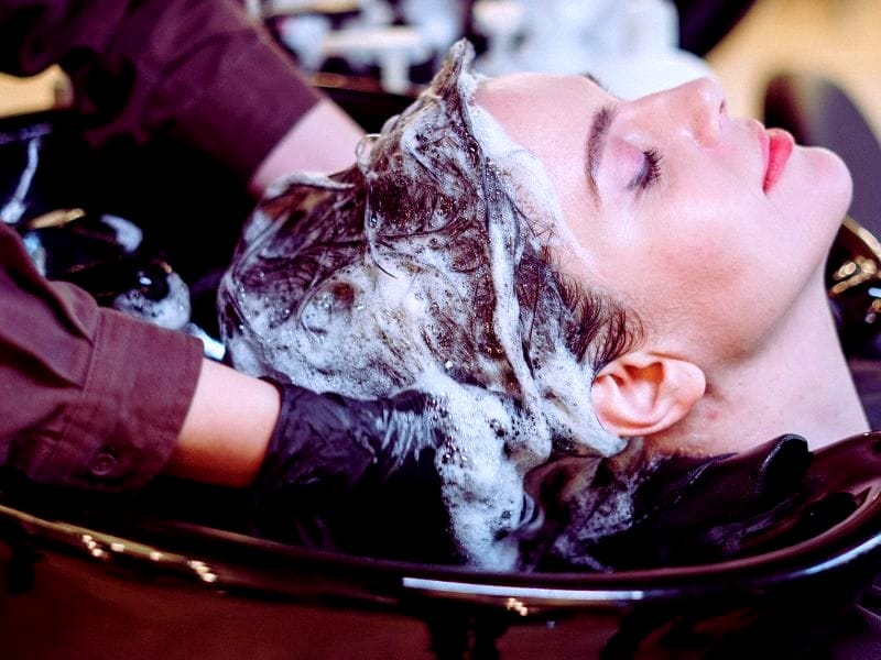 toiClient receiving a hair wash using toxic hair free products, risking scalp irritation and hair damage.