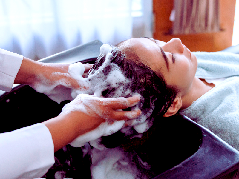 Client receiving a hair wash at a salon using vegan hair products for a sustainable and eco-friendly experience.