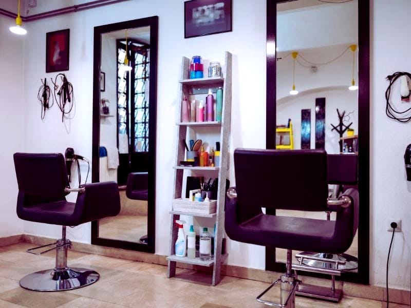 Modern hair salon interior with styling chairs, mirrors, and a shelf displaying vegan haircare products for ethical beauty solutions.