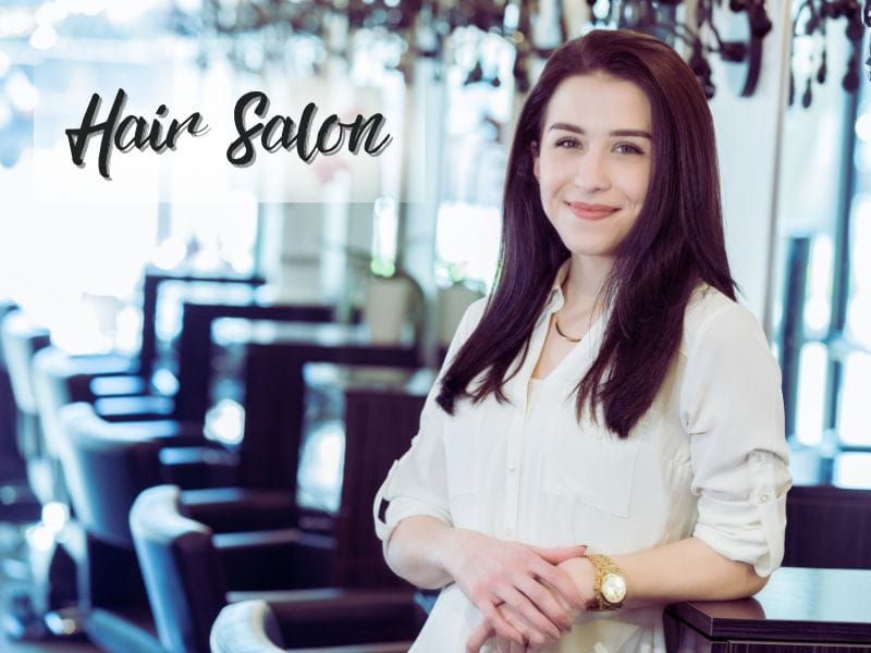 A confident salon owner standing in a bright and modern hair salon, promoting cruelty-free haircare products.