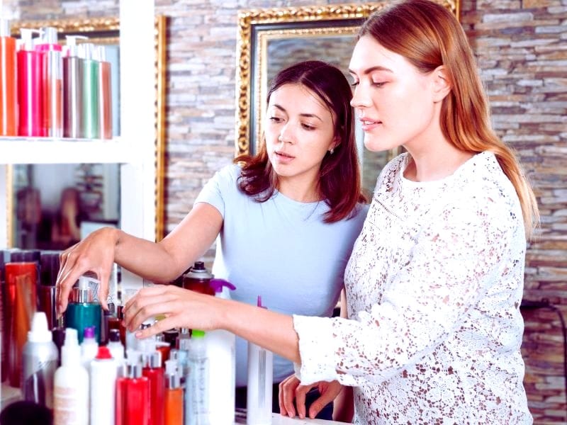 Two women exploring salon product options, emphasizing strategies to boost salon revenue through retailing.