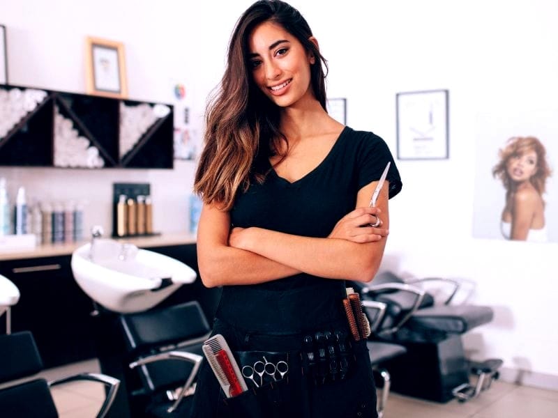 Confident hairstylist in a modern salon promoting clean beauty haircare for healthy, eco-friendly styling.