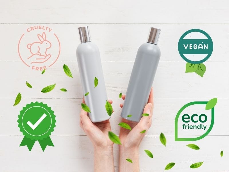 Hands holding eco-friendly, vegan, cruelty-free product bottles with green leaves and ethical certification badges.