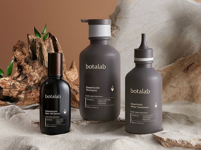 Elegant display of Botalab cruelty-free shampoo, hair oil serum, and water treatment products in natural tones.