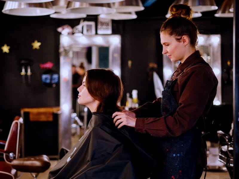 Hair stylist attending to a customer in a salon, highlighting the importance of ethical hair care for sustainable beauty.