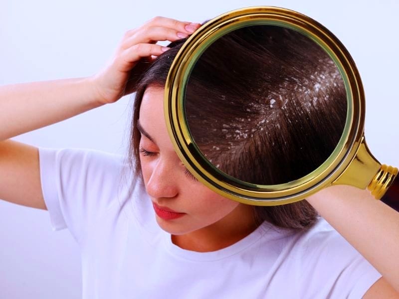 Close-up of a woman examining her scalp with a magnifying glass, highlighting the benefits of using vegan conditioner for healthy hair.