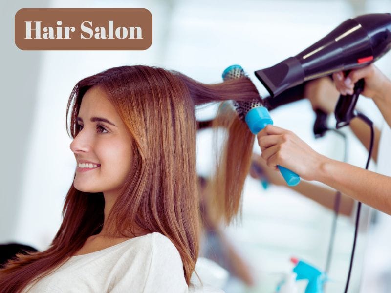 "Smiling woman gets a blowout using vegan hair care essential for salon success and sustainable beauty.