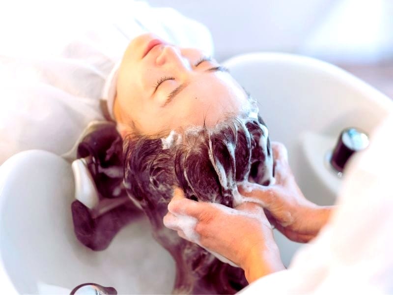 Hair Damage from Shampooing: A person receiving a hair wash at a salon.