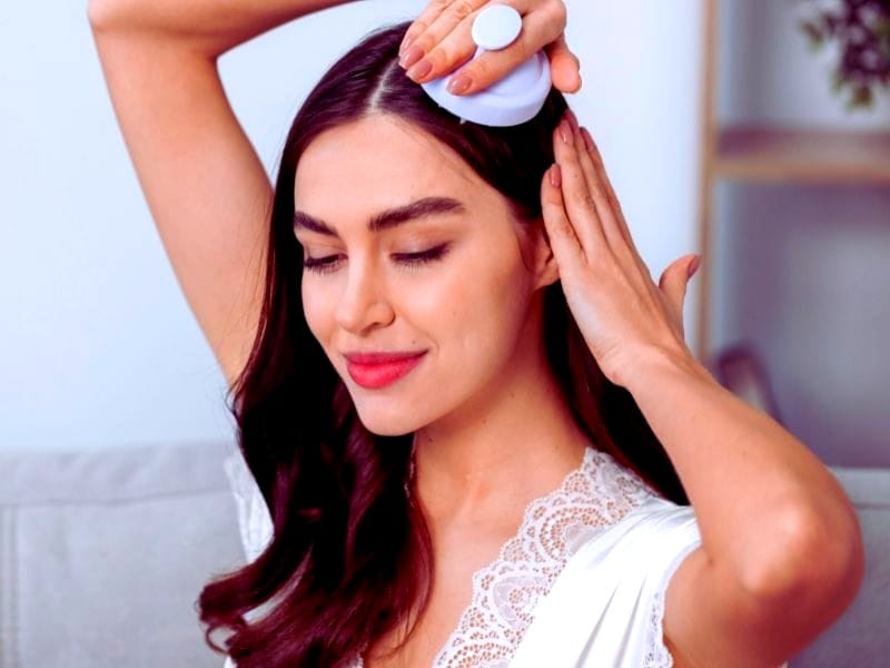 A woman with long, shiny hair using a scalp massager, highlighting the best hairbrushes for salons.