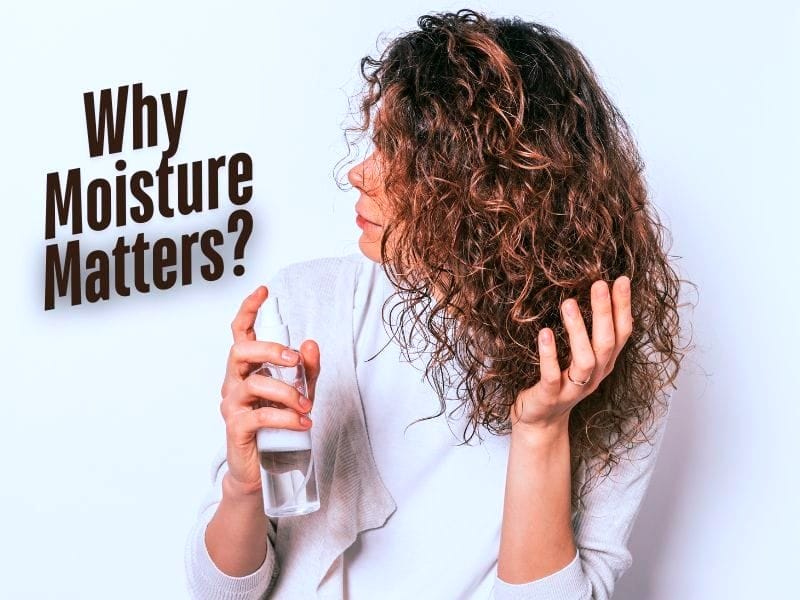 Curly-haired woman holding a spray bottle, emphasizing the importance of moisture for healthy, hydrated hair.