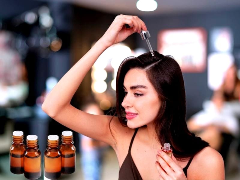 Woman applying hair oil with a dropper in a salon setting, promoting nourishment and scalp health.