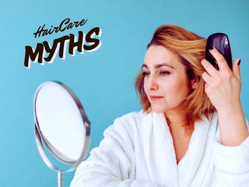 Woman brushing her hair while looking in the mirror, debunking common hair care misconceptions.