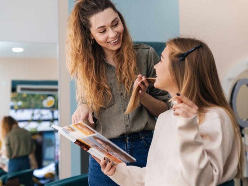 "Hairdresser educating a client about haircare, ensuring healthy hair choices for vibrant, nourished locks.