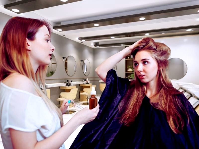 A hairstylist discussing scalp treatment with a concerned client in a modern salon.