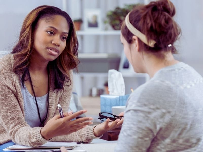 Two women having a serious conversation; one is educating a hair client about proper hair care and products.